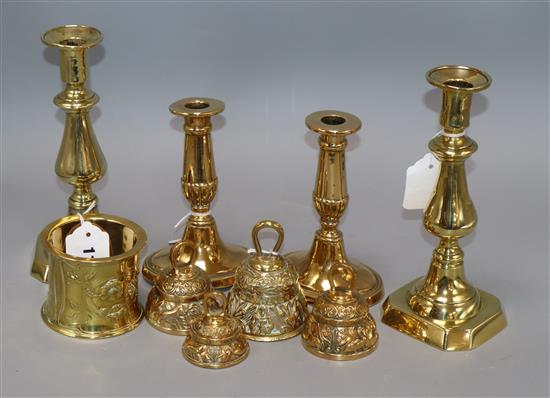 Two pairs of brass candlesticks, four embossed brass table bells of varying sizes and an Art Nouveau brass pot